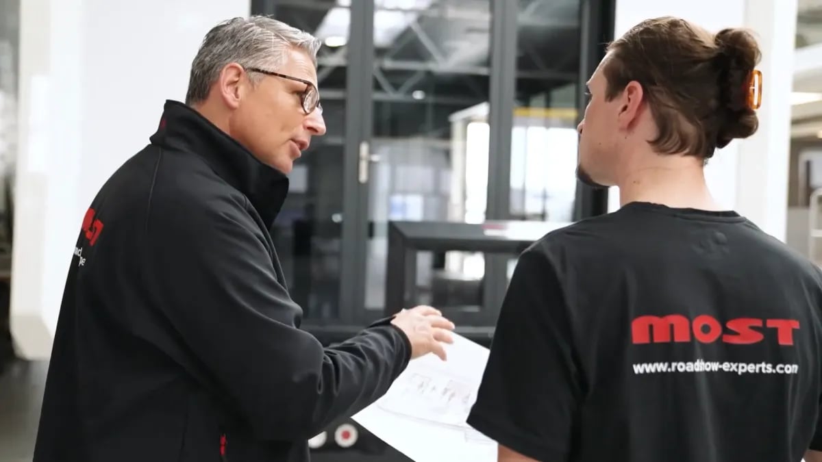 Zwei MOST-Mitarbeiter besprechen einen Plan in der Halle