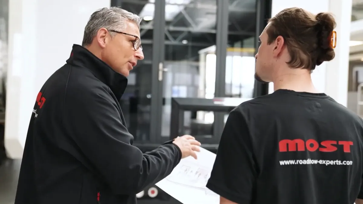 Zwei MOST-Mitarbeiter besprechen einen Plan in der Halle